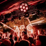 Crowd dancing beneath red lights at L'Arc Paris