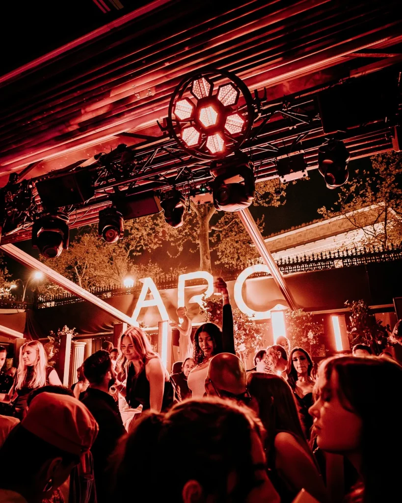 Crowd dancing beneath red lights at L'Arc Paris
