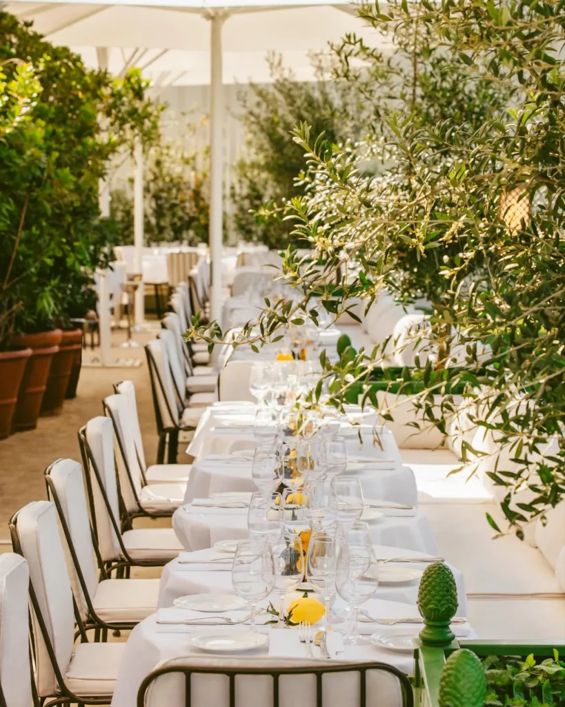 Long outdoor dining table surrounded by greenery at Loulou Paris