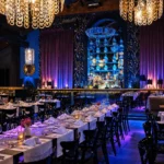 Elegant dining room with chandeliers and a stage at Maison Milano