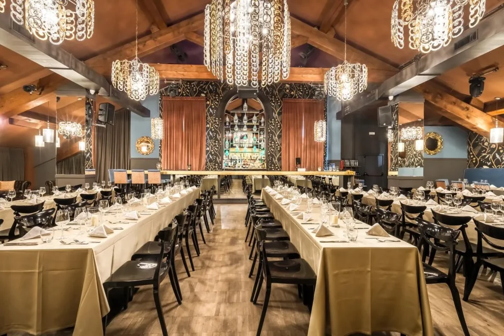 Long dining room with chandeliers and elegant table settings at Maison Milano
