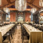 Long dining room with chandeliers and elegant table settings at Maison Milano