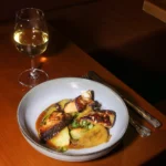 Gourmet plated dish served with wine at Pachamama Paris