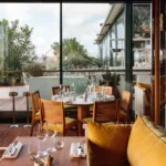 Elegant restaurant interior with large windows at Perruche Paris