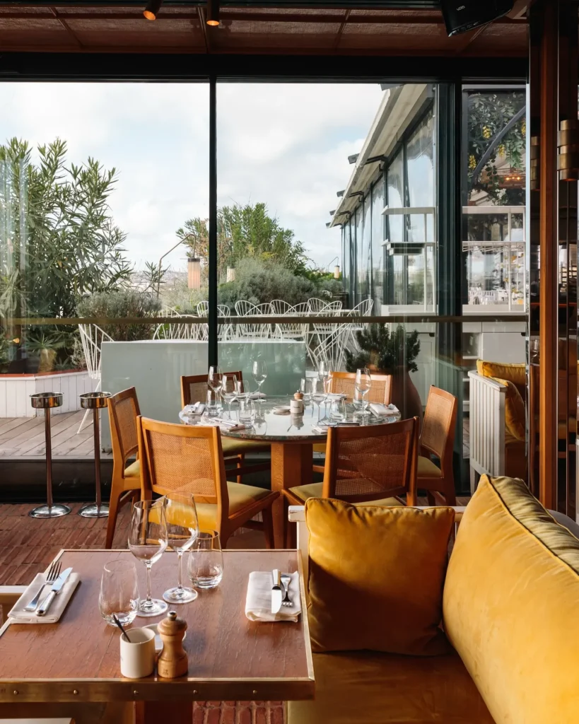 Elegant restaurant interior with large windows at Perruche Paris