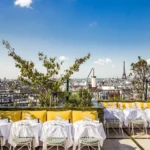 Rooftop dining tables at Perruche Paris under a blue sky