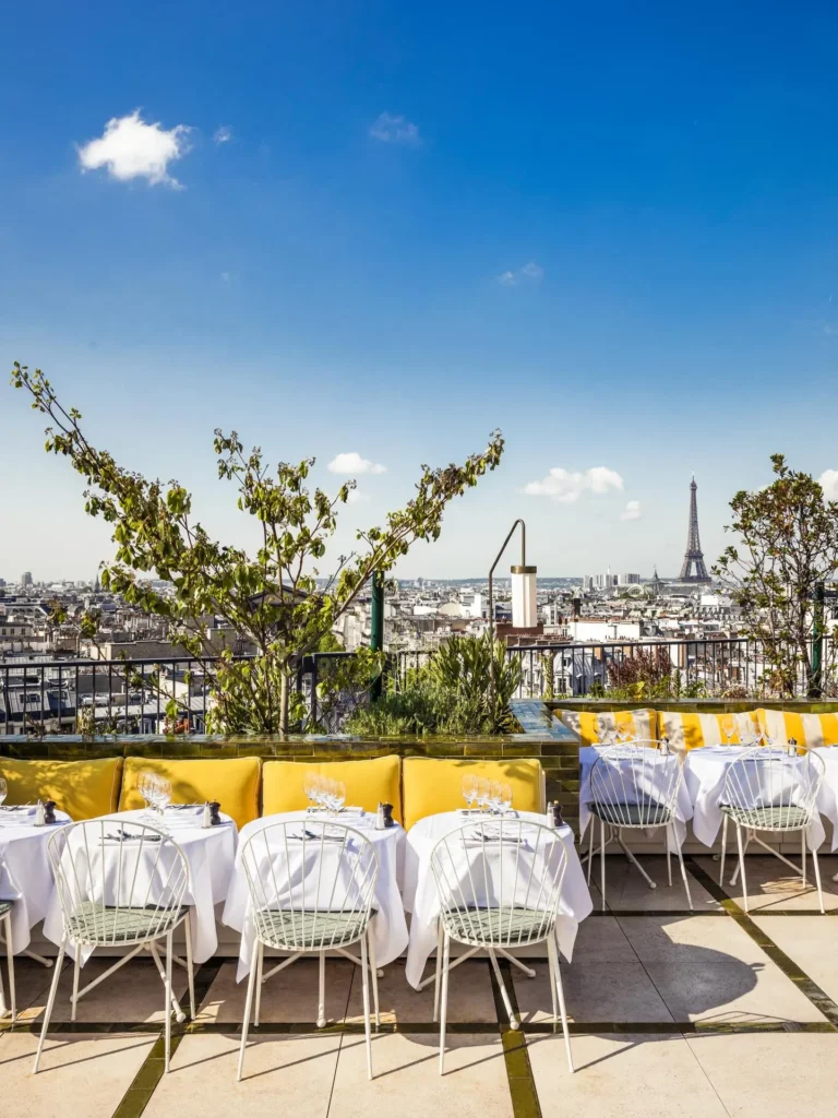 Rooftop dining tables at Perruche Paris under a blue sky