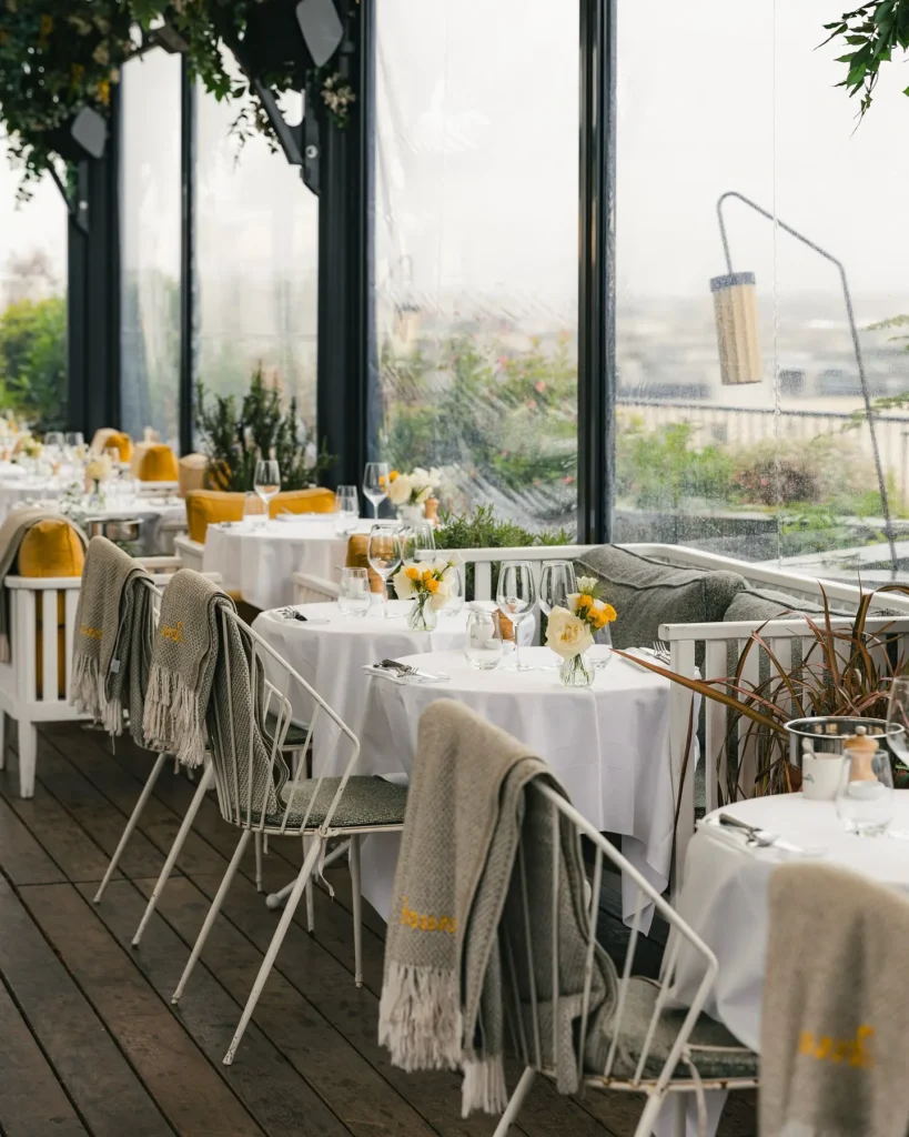 Rooftop dining area at Perruche Paris with views of Paris