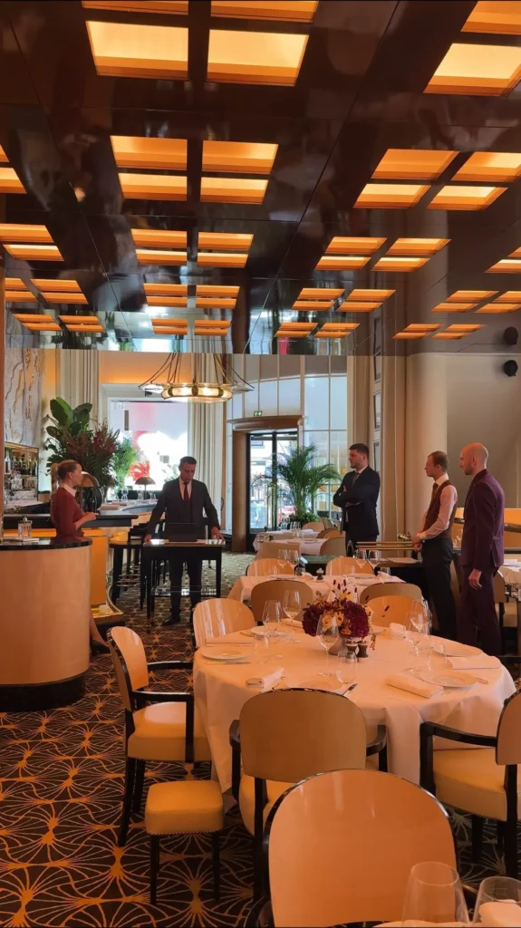 Warmly lit dining room with elegant tables at Plaza Athenee in Paris