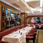 Elegant dining room with red chairs and colorful artwork at Scott's Mayfair