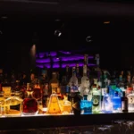 Illuminated bar stocked with bottles inside STK Milan