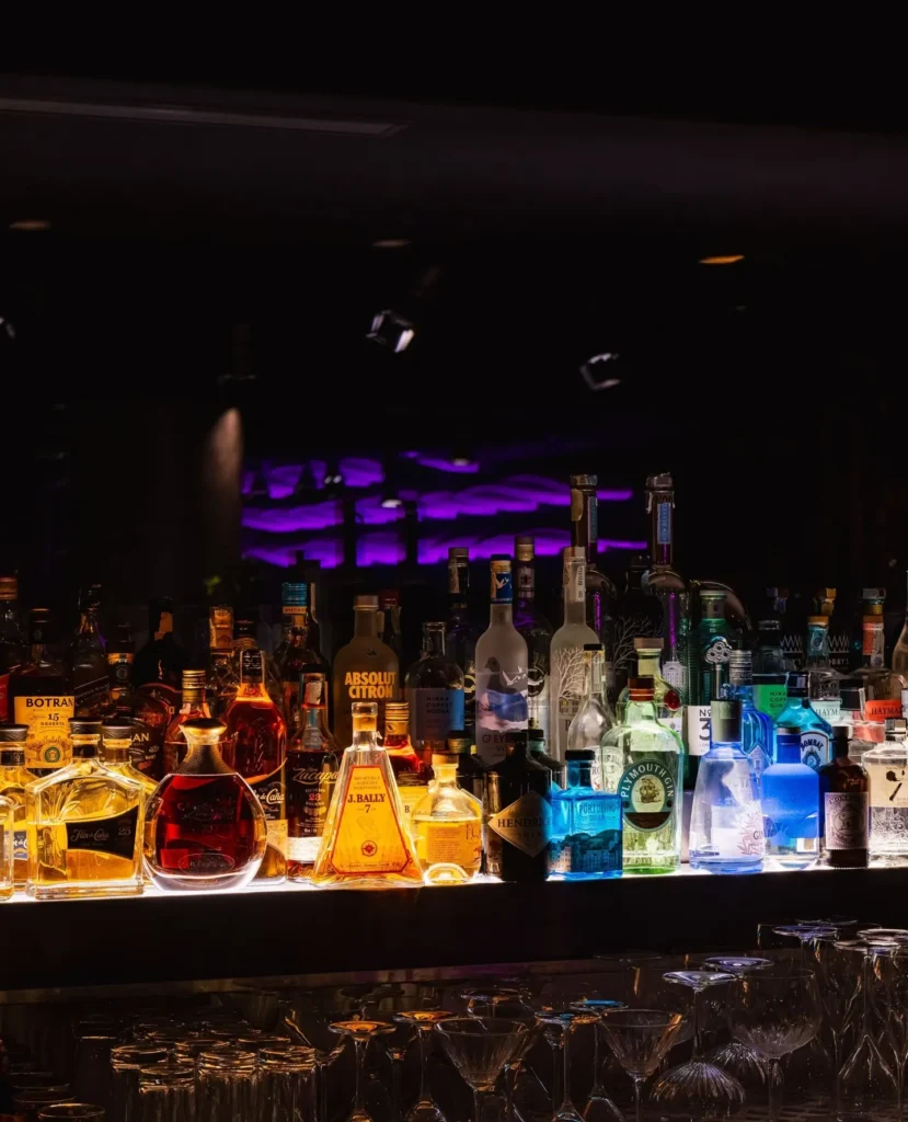 Illuminated bar stocked with bottles inside STK Milan