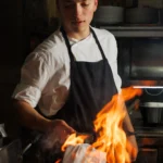 Chef grilling steak over an open flame at STK Milan