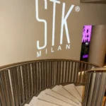 STK Milan entrance with its illuminated logo and staircase
