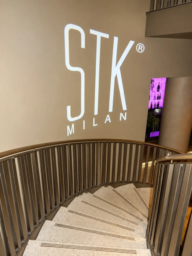 STK Milan entrance with its illuminated logo and staircase