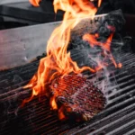 Grilled steak cooking over an open flame at STK Milan