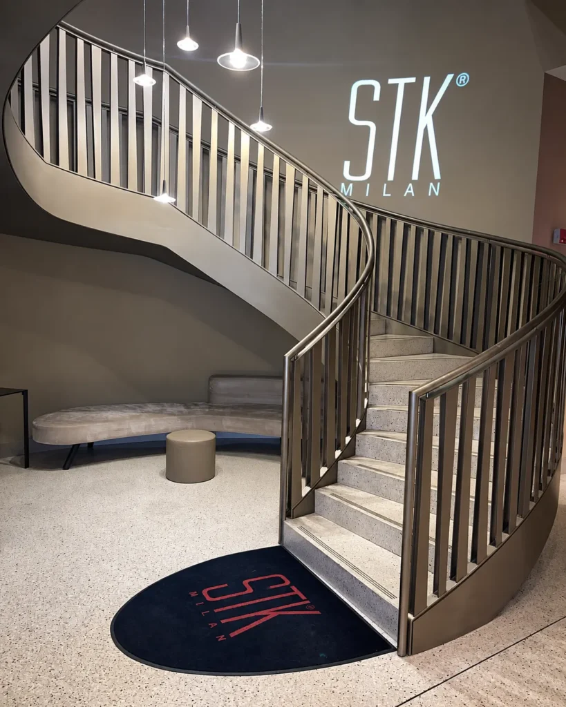 Curved staircase and STK Milan logo inside the restaurant