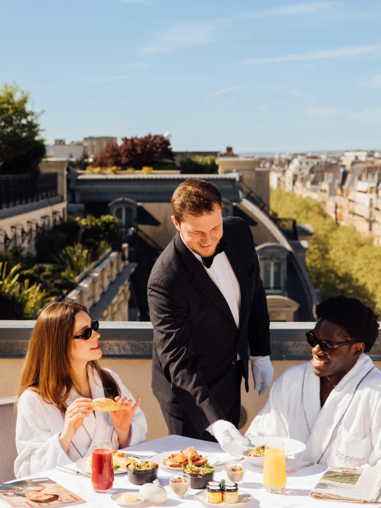 Guests dining on a rooftop terrace with Paris views at The Peninsula Paris