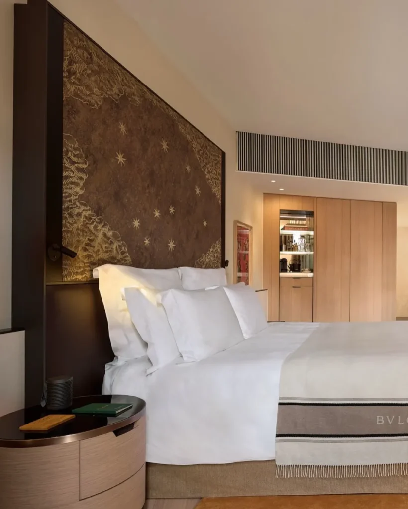 Elegant hotel bedroom with white linens, textured wall finishes and warm contemporary furnishings at Bulgari Hotel Milano