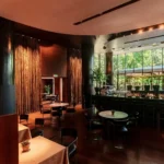 Elegant lounge at Bulgari Hotel Milano with dark wood furnishings, comfortable seating and views of the garden