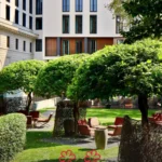 Lush green garden with manicured hedges, outdoor seating and the hotel facade at Bulgari Hotel Milano