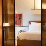 Luxury hotel bedroom with crisp white bedding, warm wood finishes and elegant contemporary furnishings at Bulgari Hotel Milano