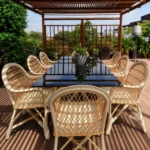 Outdoor dining terrace with woven chairs, a long table and a timber pergola at Bulgari Hotel Milano