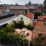 Rooftop view across Milan with historic buildings and a landscaped hotel terrace at Bulgari Hotel Milano