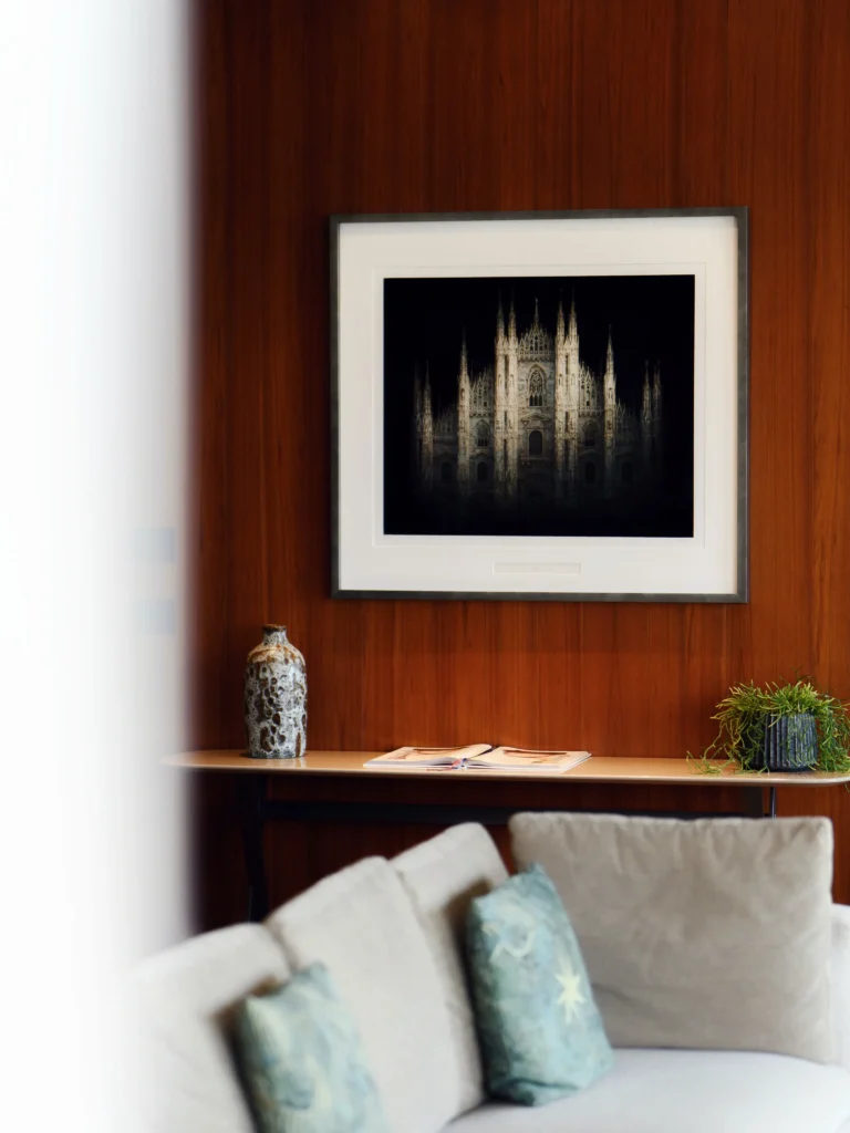 Refined hotel suite interior with a wood-paneled wall, framed artwork and elegant upholstered seating at Bulgari Hotel Milano