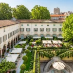 Elevated view of the green courtyard garden with outdoor seating and historic buildings at Four Seasons Hotel Milano
