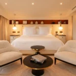 Symmetrical luxury bedroom with a king-size bed, upholstered chairs and warm lighting at Four Seasons Hotel Milano
