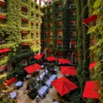 Outdoor dining terrace with red parasols and greenery in the courtyard at Hôtel Plaza Athénée Paris