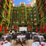 Outdoor restaurant tables in a leafy courtyard surrounded by ivy-covered architecture at Hôtel Plaza Athénée Paris