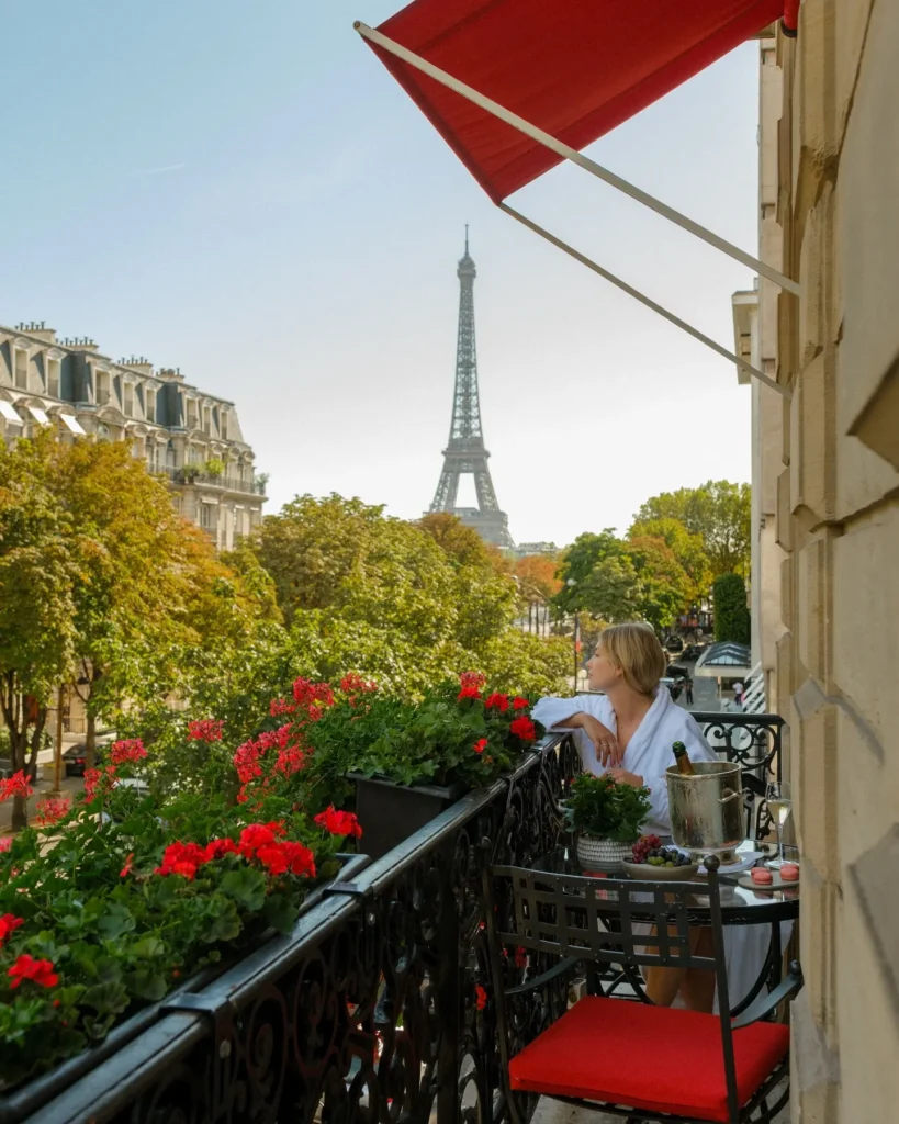 Flower-filled terrace with red awnings and views of the Eiffel Tower at Hôtel Plaza Athénée Paris