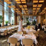 Sophisticated restaurant dining room with golden ceiling lights and elegant table settings at Hôtel Plaza Athénée Paris