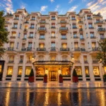 Elegant exterior facade of Hôtel Plaza Athénée Paris beneath a colorful evening sky