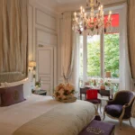Elegant hotel suite with a refined bedroom, soft neutral colors and classic Parisian furnishings