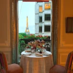 Intimate dining table beside a tall window overlooking Paris at Hôtel Plaza Athénée