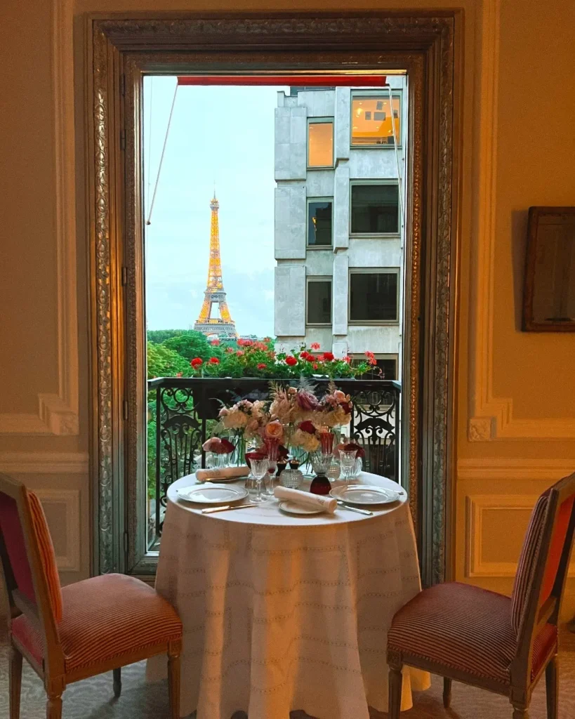 Intimate dining table beside a tall window overlooking Paris at Hôtel Plaza Athénée