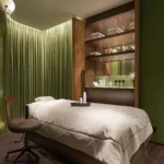 Irene Forte Spa treatment room at The Carlton Milan featuring a massage bed, green-toned walls, soft lighting, and natural textures