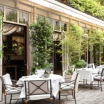 Bright garden restaurant terrace with white tables and greenery at La Réserve Paris