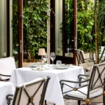Outdoor dining tables surrounded by greenery at La Réserve Paris