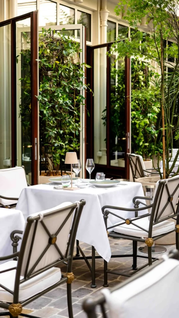 Outdoor dining tables surrounded by greenery at La Réserve Paris