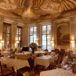 Ornate dining room at Le Meurice Paris with gilded decor and chandeliers