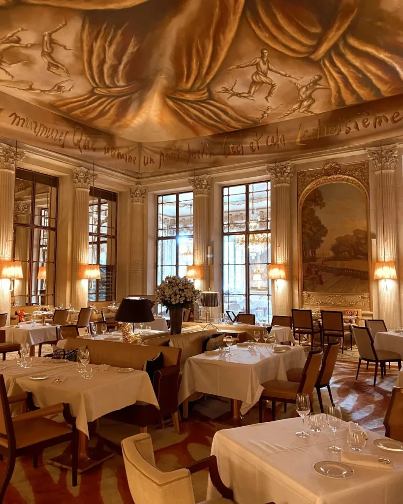 Ornate dining room at Le Meurice Paris with gilded decor and chandeliers