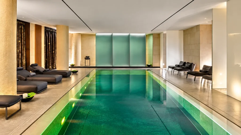Symmetrical indoor spa pool with turquoise water, stone walls and contemporary lounge seating
