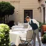 Outdoor dining table prepared with white linens and elegant tableware in the landscaped courtyard of Mandarin Oriental Milan