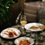 Outdoor dining table with gourmet dishes, wine glasses and greenery in a secluded garden setting at Mandarin Oriental Milan