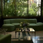 Contemporary lounge with deep green sofas, a glass coffee table and floor-to-ceiling windows overlooking greenery at Mandarin Oriental Milan