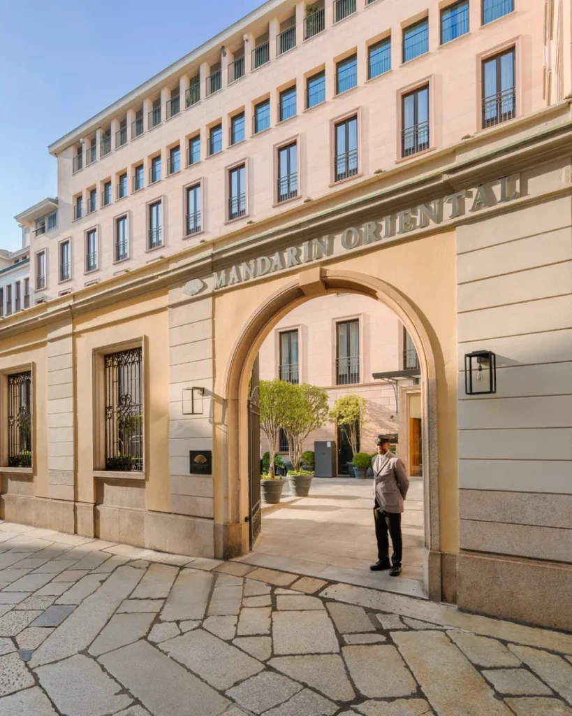 Historic cream-colored facade and arched entrance of Mandarin Oriental Milan on a cobblestone street